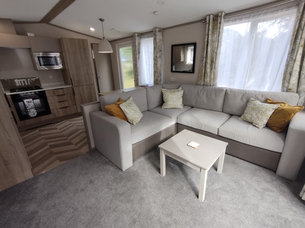 Living room / lounge area inside our static caravan with comfy sofas, table and plush carpet. Holiday rental in Newquay Cornwall, static caravan holiday. 